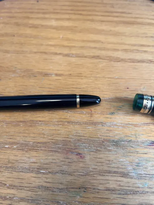 The finial of the pen, showing how it's a different color compared to the body